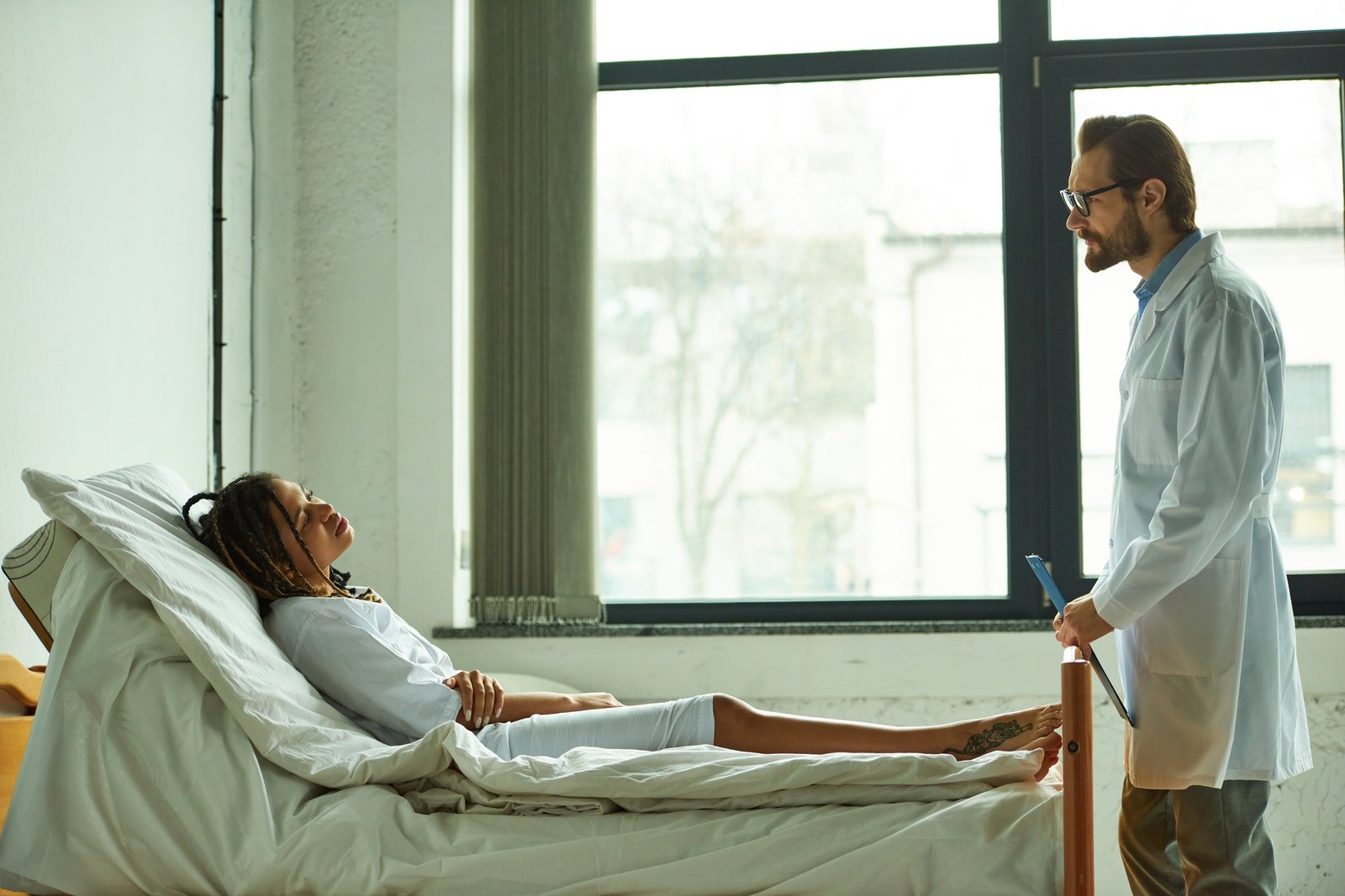 doctor standing with clipboard near african american woman, private ward, hospital, consultation