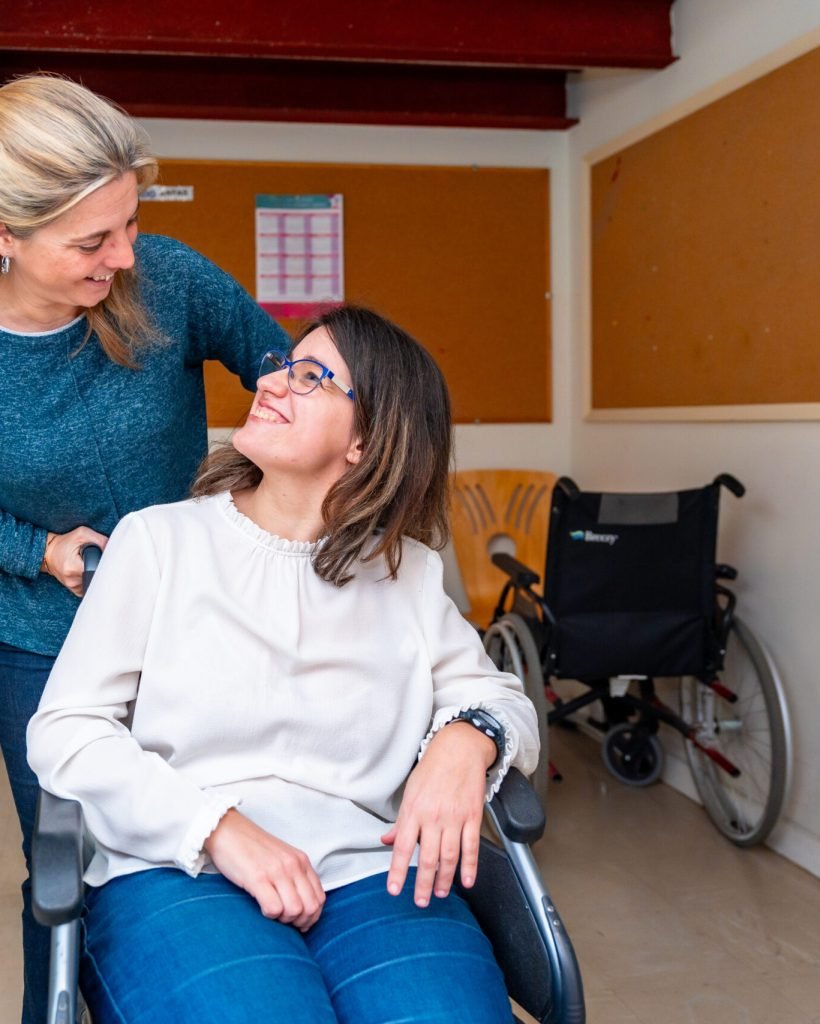 Caregiver pushing the wheelchair of a disabled woman in a day center for people with special needs