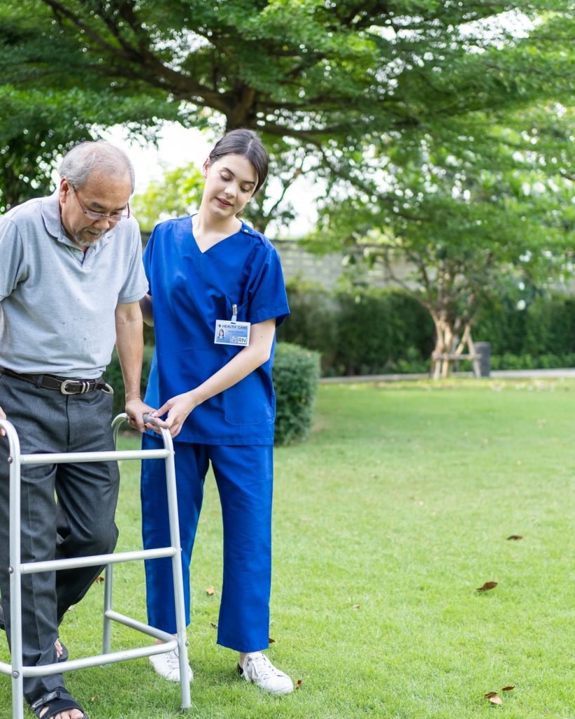 Asian young woman nurse at nursing home take care disabled senior man at backyard.