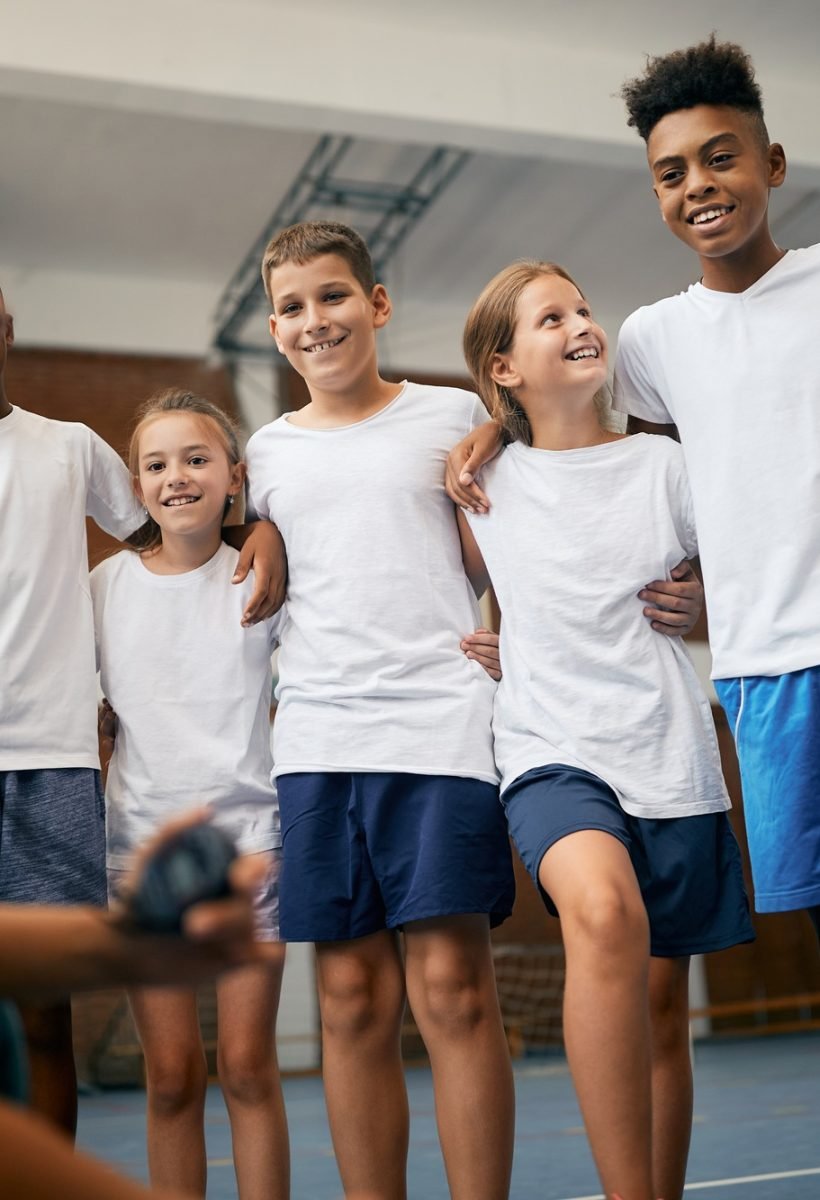 Happy school kids having physical education class with sports teacher at elementary school.